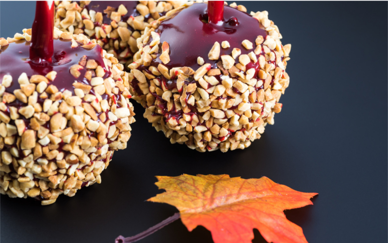 Close up of candy apples with nuts on a black background.