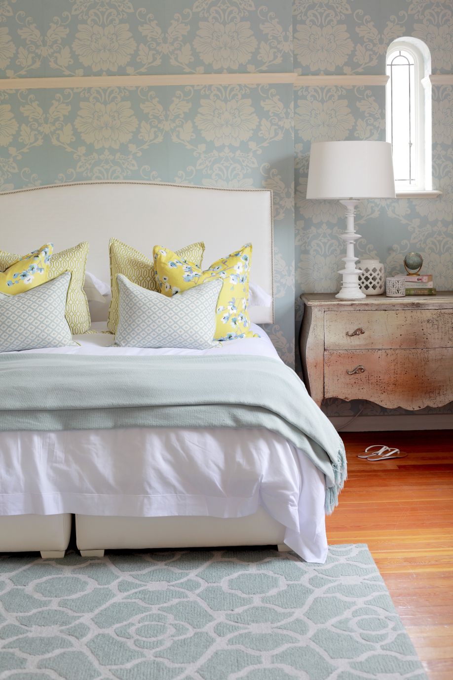Tapete und Teppich in floralem Pastellblau, kombiniert mit dem zeitlosen Mustermix der Kissen auf einem Bett